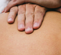Hands on back of patient for Downtown Calgary Chiropractic Services